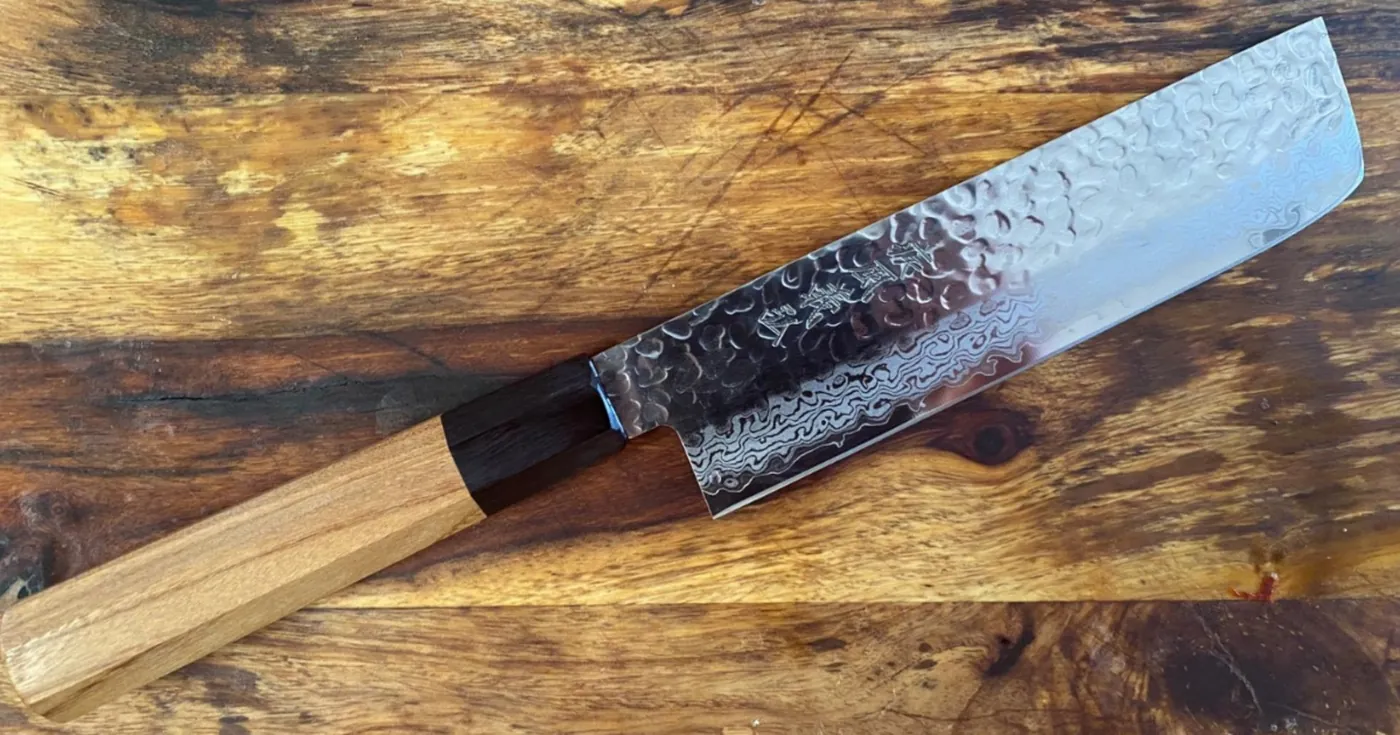 Cuchillo japonés de acero damasco sobre tabla de madera
